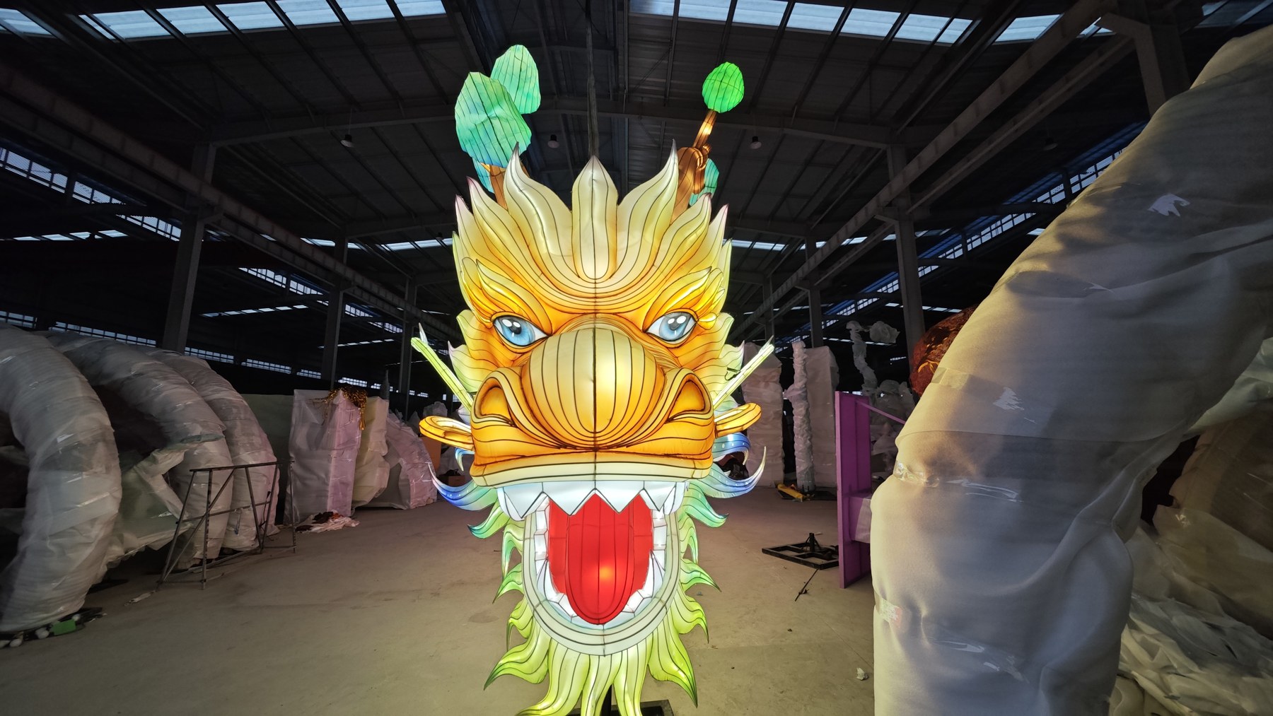 Front view of an illuminated dragon face with golden brows, blue eyes and green whiskers