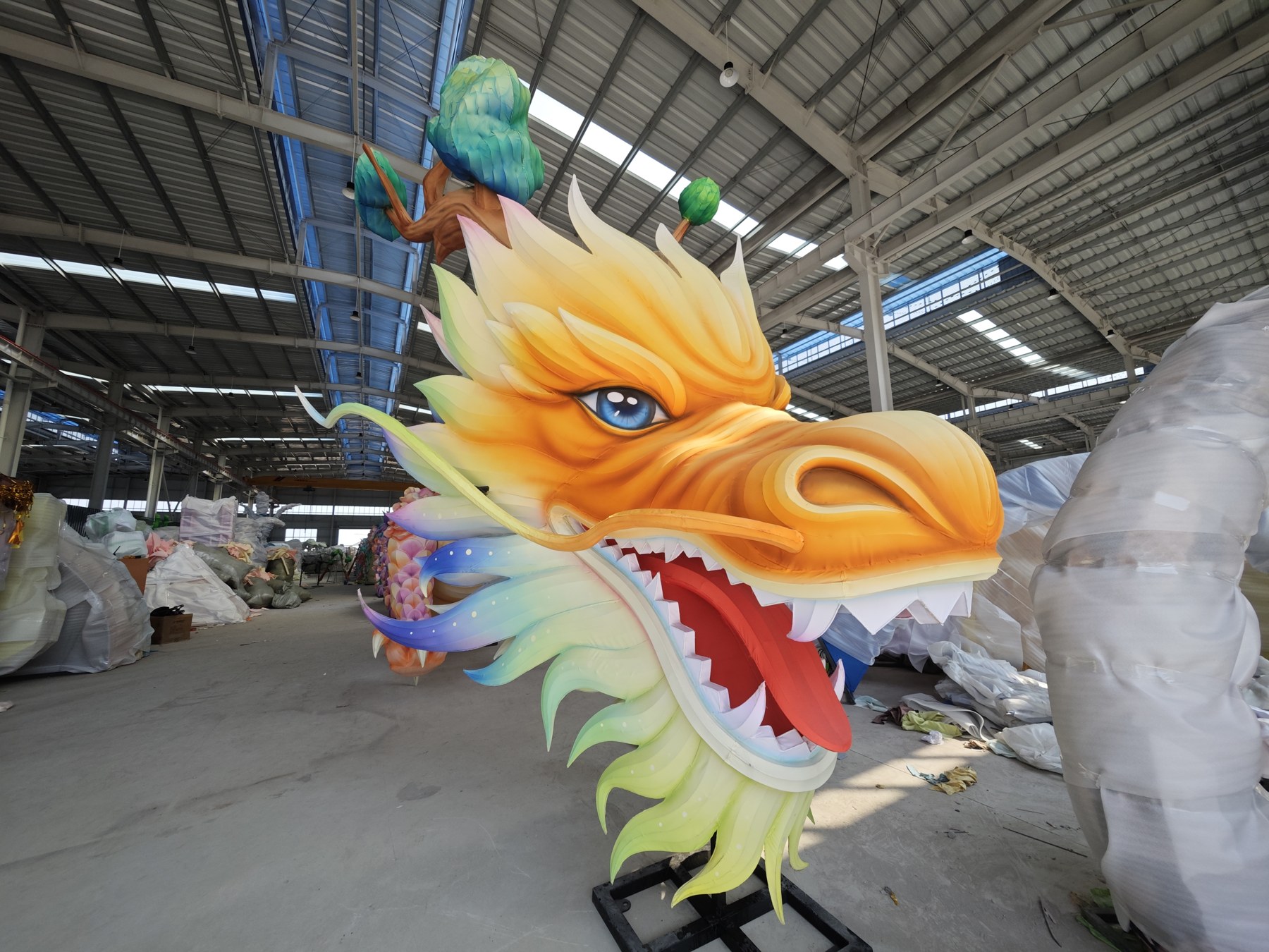 Golden dragon lantern head with shaped brows, painted eyes and layered cheek details in daylight